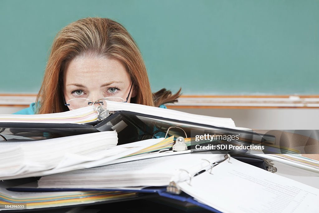 Woman hiding behind school binders in classroom