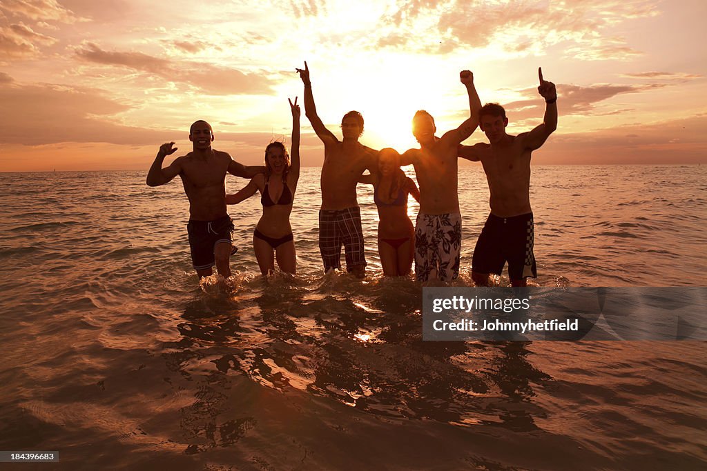A silhouette of friends in the sea at sunset