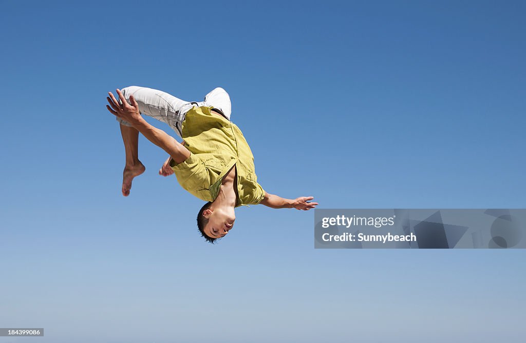 Man doing somersault in the air against blue sky