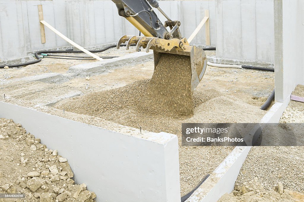 Excavator Bucket Filling Basement with Rock