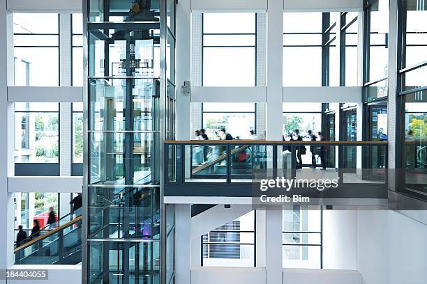 modern business hall with blurred people, stairs, escalators and elevator - crowded elevator stockfoto's en -beelden
