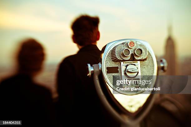 close up of binoculars with two people in background - ellis island stock pictures, royalty-free photos & images