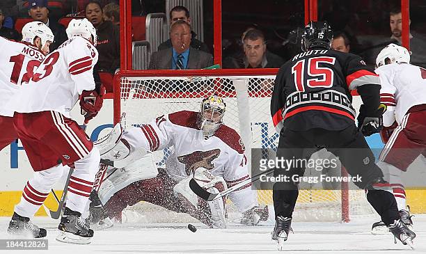 David Moss of the Phoenix Coyotes and teammate Oliver Ekman-Larsson help goaltender Mike Smith defend the net against Tuomo Ruutu of the Carolina...