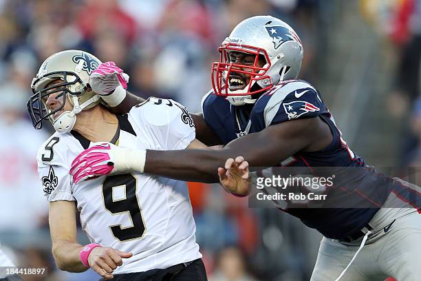 Quarterback Drew Brees of the New Orleans Saints gets off a pass while being hit by defensive end Chandler Jones of the New England Patriots during...