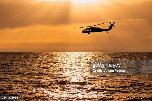 utility military helicopter  at sunset over the sea - attack helicopter stock pictures, royalty-free photos & images