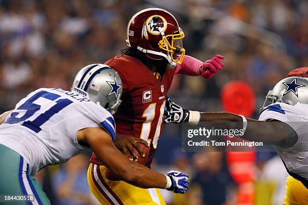 Robert Griffin III of the Washington Redskins fumbles the ball while being sacked by Kyle Wilber of the Dallas Cowboys and George Selvie of the...