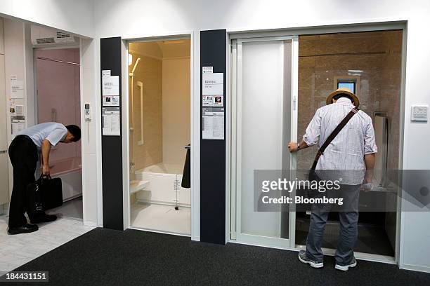 Customers look at Lixil Group Corp.'s bathroom units displayed at the company's showroom in Tokyo, Japan, on Friday, Oct. 11, 2013. Lixil and...