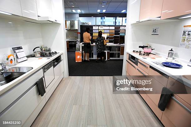 Customer, right, looks at samples of Lixil Group Corp.'s kitchen cabinet doors with an employee while kitchen units stand on display at the company's...