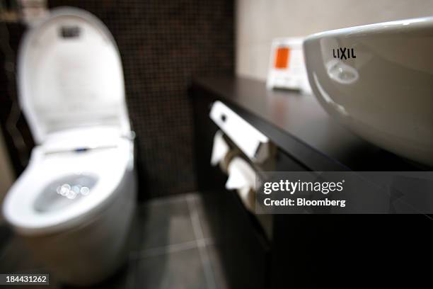 The Lixil Group Corp. Logo is seen on a wash basin as a Satis toilet stands on display at the company's showroom in Tokyo, Japan, on Friday, Oct. 11,...