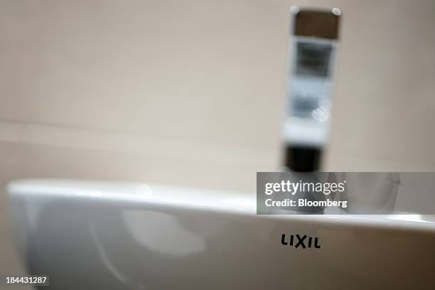 The Lixil Group Corp. Logo is displayed on a wash basin at the company's showroom in Tokyo, Japan, on Friday, Oct. 11, 2013. Lixil and Development...