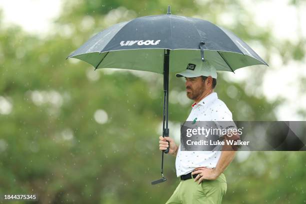 Louis Oosthuizen of South Africa looks on while holding an umbrella from the 2nd green as rain falls on Day Four of the Alfred Dunhill Championship...