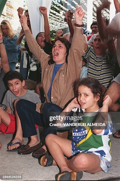 Residents of a neighborhood in Rio de Janeiro applaud before a television monitor 31 May as team Brazil scores a goal during a friendly soccer match...