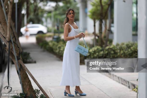 Jessica De Oliveira seen wearing gold earrings, Riani white strappy long dress, Jacquemus light blue suede leather Bambino Long bag, Dior gold...