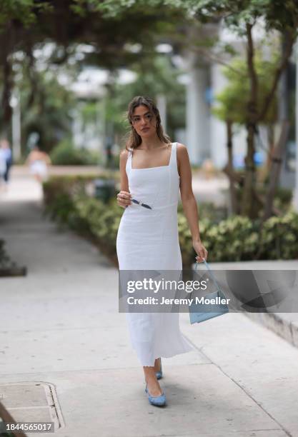 Jessica De Oliveira seen wearing gold earrings, Riani white strappy long dress, Jacquemus light blue suede leather Bambino Long bag, Dior gold...