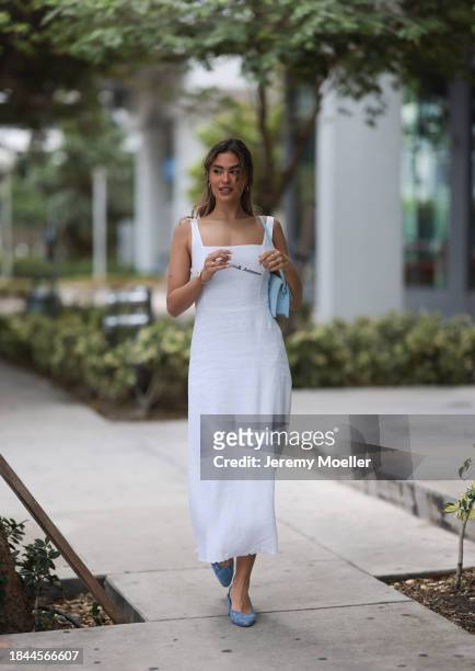 Jessica De Oliveira seen wearing gold earrings, Riani white strappy long dress, Jacquemus light blue suede leather Bambino Long bag, Dior gold...