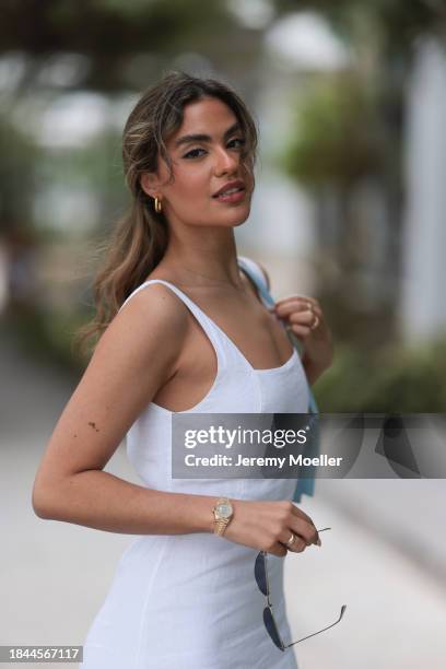 Jessica De Oliveira seen wearing gold earrings, Riani white strappy long dress, Jacquemus light blue suede leather Bambino Long bag, Dior gold...