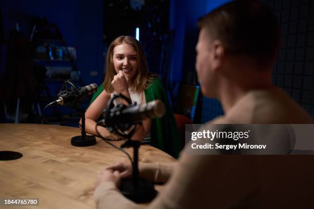 smiling young woman talking to colleague in modern studio with microphones - maestro de ceremonias fotografías e imágenes de stock