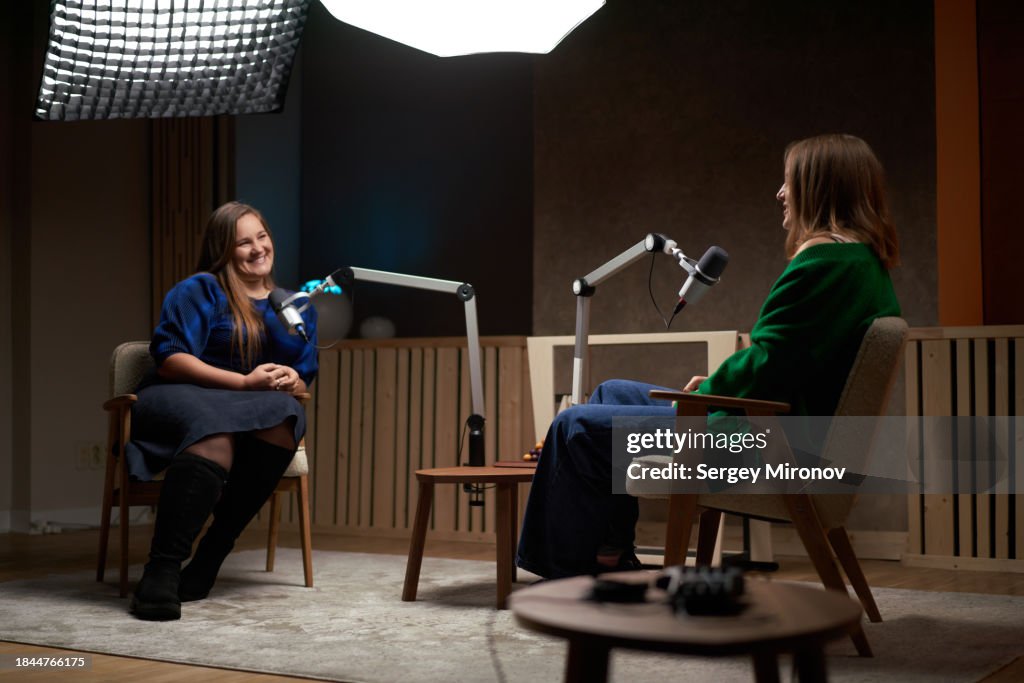 Positive women chatting while recording podcast