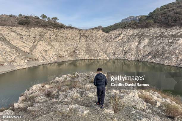 Water lines are visible as Joel Ramos, photographer's son, walks along the bank of Siurana reservoir on December 09, 2023 in Cornudella de Montsant,...