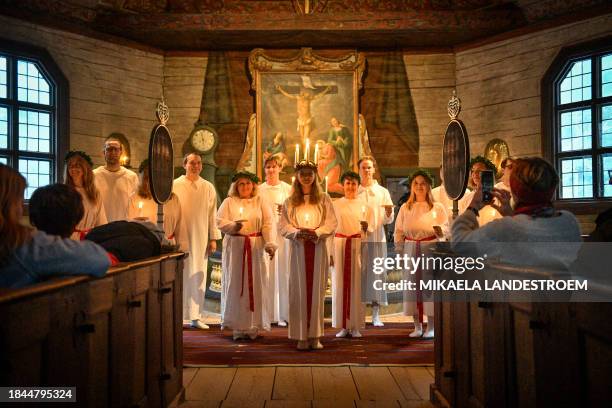 Youth wears a crown of candles in Seglora church at Skansen in Stockholm, Sweden on December 13, 2023 to celebrate the Christian feast of Saint...