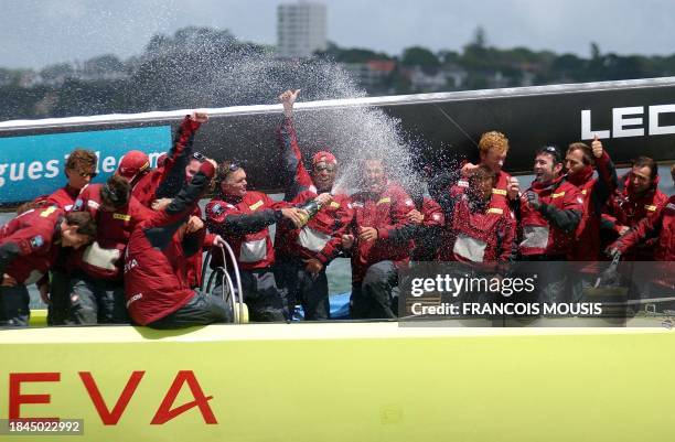 France's Le Defi Areva skipper Luc Pillot celebrates with a bottle of champagne and crew after winning the race against Italy's Mascalzone Latino in...