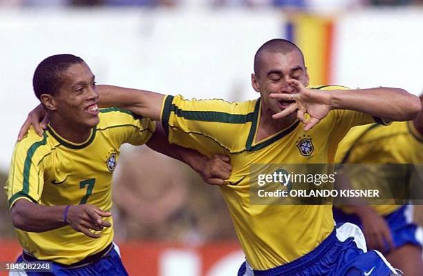 Brazilian soccer player Fabio Bilica, right, kisses his wedding ring as he and teammate Ronaldinho Gaucho celebrate their first goal against Uruguay...