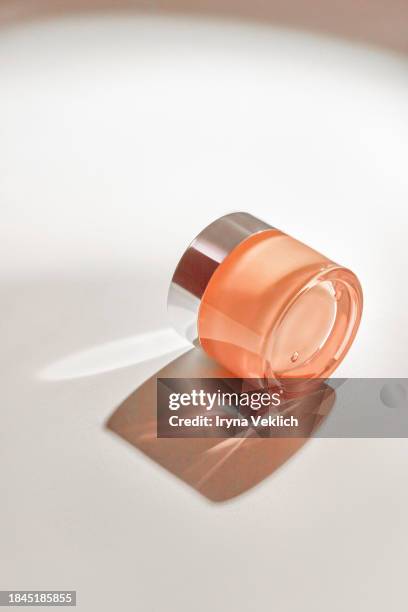 cosmetic product in glass jar - skincare face cream, refreshing hydration water cream or hand cream in natural pastel pink beige peach color on white colour background with shadow. - crema viso foto e immagini stock