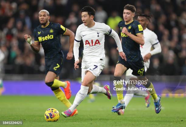 Son Heung-Min of Tottenham Hotspur runs with the ball whilst under pressure from Joelinton and Lewis Miley of Newcastle United during the Premier...