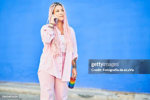 chica joven hablando por teléfono sobre un fondo azul al aire libre - teléfono stock pictures, royalty-free photos & images