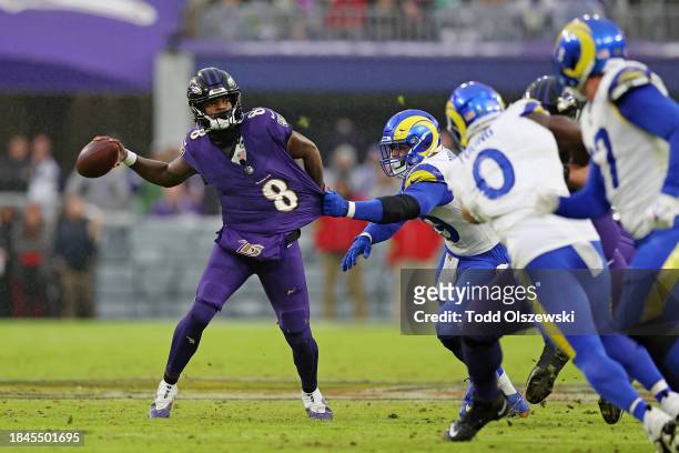 Lamar Jackson of the Baltimore Ravens throws a pass while being tackled by Aaron Donald of the Los Angeles Rams during the third quarter at M&T Bank...