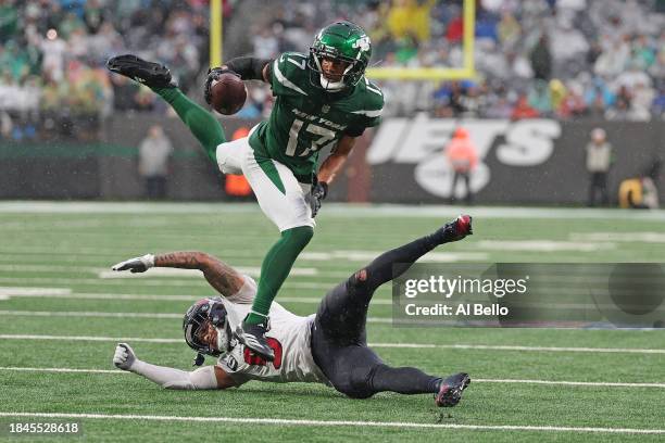 Garrett Wilson of the New York Jets jumps over Jalen Pitre of the Houston Texans during the third quarter at MetLife Stadium on December 10, 2023 in...