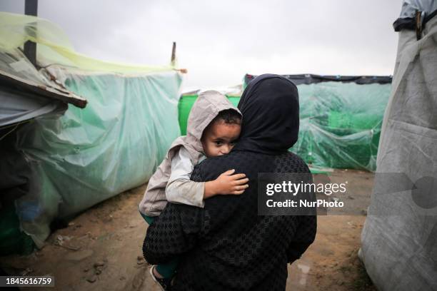 Palestinians are taking refuge amid the rain at a camp for displaced people in Deir El-Balah, in the central Gaza Strip, as battles continue between...