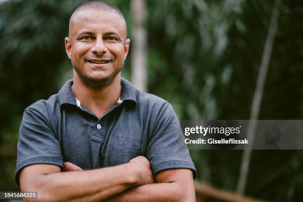 smiling man standing outside on a his patio with a scenic view - poloshirt stockfoto's en -beelden