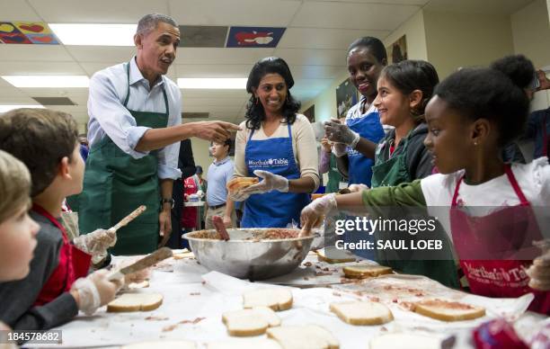 President Barack Obama talks with children and adult volunteers that are making peanut butter and jelly sandwiches at Martha's Table in Washington,...