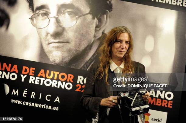 Singer Patti Smith poses with her polaroid camera in front of a giant poster of late Chilean writer Roberto Bolano in Madrid on November 26, 2010...