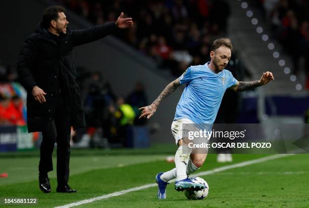 Lazio's Italian midfielder Manuel Lazzari controls the ball as Atletico Madrid's Argentinian coach Diego Simeone gestures close to him during the...
