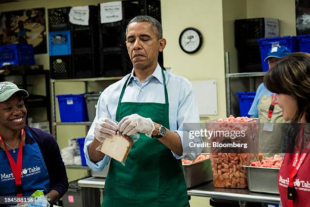 President Barack Obama, center, tries to close a plastic bag while bagging sandwiches during a visit to furloughed federal workers volunteering at...