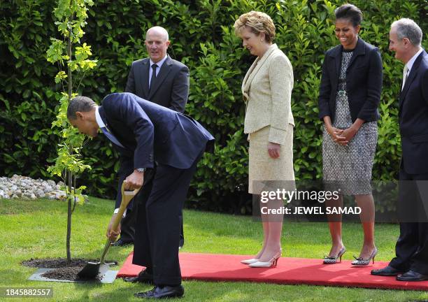 President Barack Obama plants a tree as First Lady Michelle Obama Irish President Mary McAleese and her husband Martin McAleese look on at the...