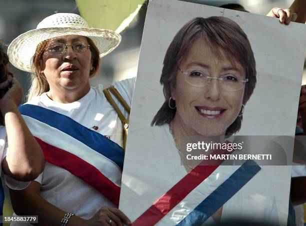 Una mujer que lleva la "banda presidencial" sostiene un afiche de la flamantea presidenta de Chile Michelle Bachelet frente al palacio de La Moneda...