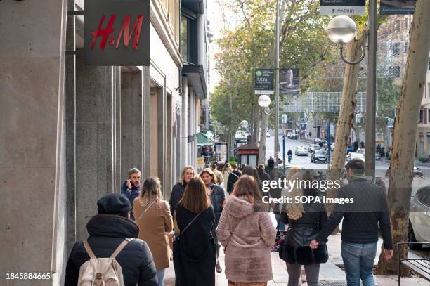 Pedestrians walk past the Swedish multinational clothing design retail company Hennes & Mauritz, H&M store in Spain.