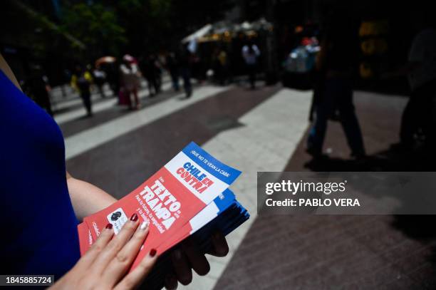 Supporter of the "En Contra " option for the new Chile's constitution proposal hands out flyers in Santiago on December 12, 2023. Four years ago,...