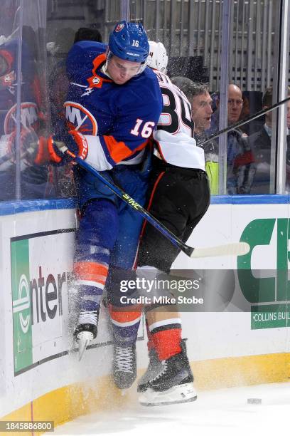 Julien Gauthier of the New York Islanders is checked into the boards by Pavel Mintyukov of the Anaheim Ducks during the first period at UBS Arena on...