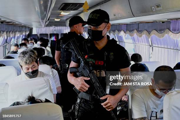 Policeman secure Chinese nationals on a bus ahead of their deportation after they were detained in a raid on a suspected sex trafficking and online...