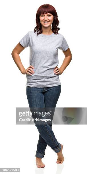sonriente mujer joven de pie con las piernas cruzadas - jeans barefoot fotografías e imágenes de stock