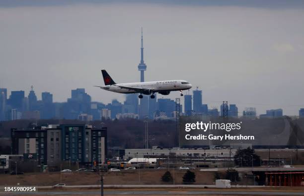 An Air Canada airplane flies in front of the downtown skyline and CN Tower as it lands at Pearson International Airport on December 10 in Toronto,...