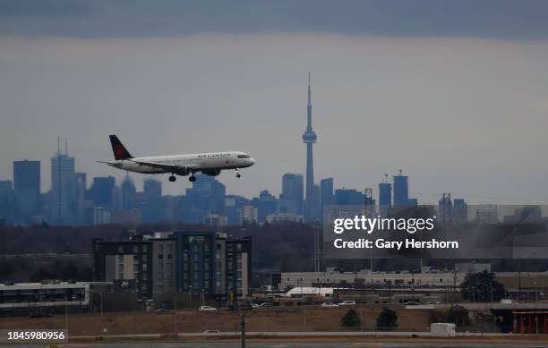 An Air Canada airplane flies in front of the downtown skyline and CN Tower as it lands at Pearson International Airport on December 10 in Toronto,...