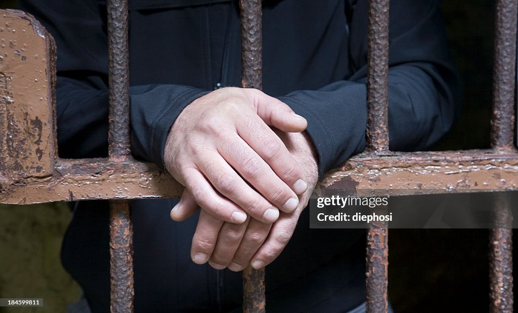 Hands protruding from jail cell bars