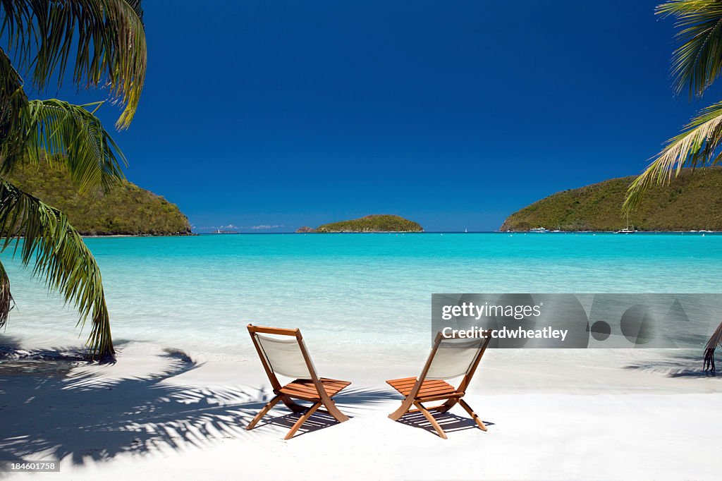 Empty chairs between palm trees at the Virgin Island's beach