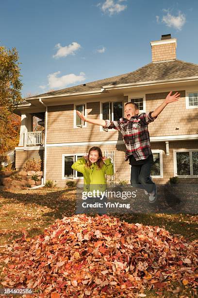 kids having fun in outdoor fall leaves clean-up - clean house stockfoto's en -beelden