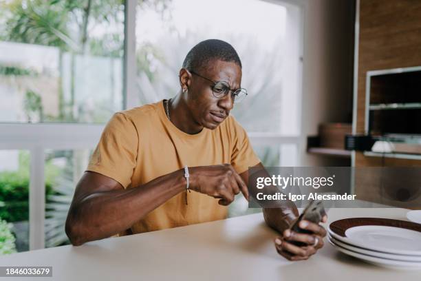 homem preocupado usando smartphone em casa - suspicion - fotografias e filmes do acervo